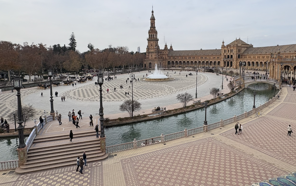 Aerial view of Plaza de España in Seville featuring a fountain, pathways, and visitors enjoying the space.